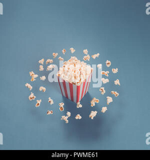 Popcorn Kernels Um einen rot gestreiften Kiste voller Popcorn fliegen Stockfoto