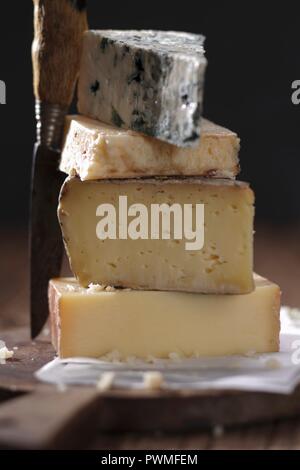 Ein Stapel von Käse auf einem Holzbrett mit Messer Stockfoto