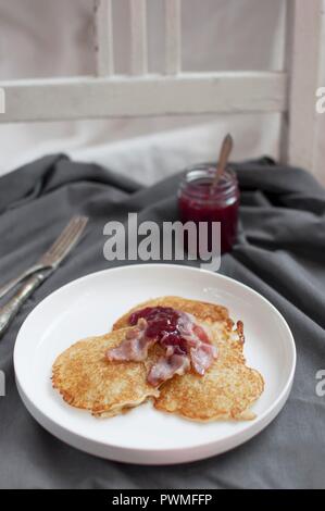 Raggmunk ist traditionelle schwedische Kartoffelpuffer, in Butter gebraten, serviert mit gebratenen Schwein und Preiselbeeren Stockfoto