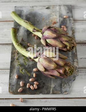 Artischocken, Bohnen und Thymian auf ein Holzbrett Stockfoto