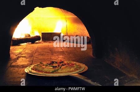 Eine Pizza in einem mit Holz befeuerten Ofen platziert Stockfoto