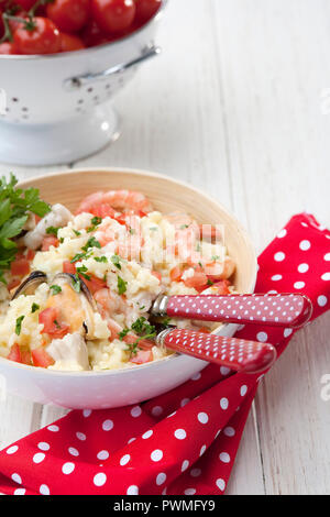 Meeresfrüchte Risotto - mit Fisch, Muskeln, Garnelen und Petersilie garnieren Kirschtomaten; im Hintergrund Stockfoto