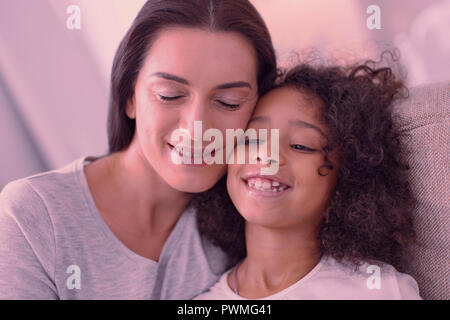 Nette junge Frau, die ihre Augen schließen begeistert Stockfoto