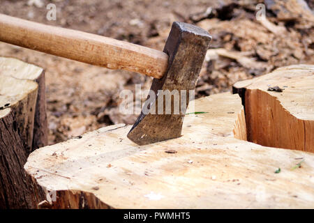 Eine Axt auf einem Holz, Baum anmelden. Eine Axt stecken in einem vor einem Stapel von Holz anmelden, bereit zum Zerkleinern und im Winter. Hartholz, Holzindustrie. Heizperiode, Stockfoto