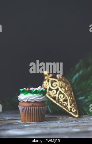 Vanilla Cupcake mit Weihnachtsdekoration, auf dunklem Hintergrund; selektive Fokus Stockfoto