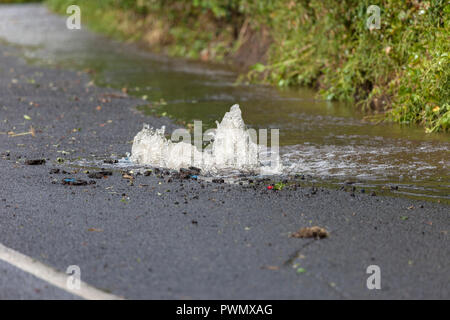 Wasser Herausspritzen von einem Platzen der Wasserleitung in der Straße, County Durham, UK Stockfoto