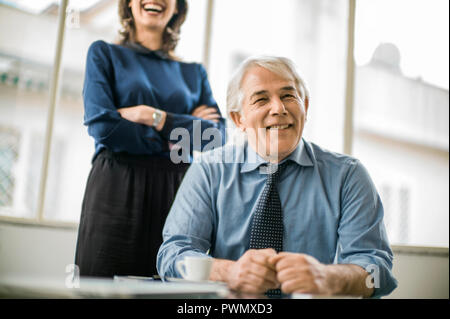 Senior Geschäftsmann in einer Besprechung sitzen wie seine jungen Mitarbeiter aussieht. Stockfoto