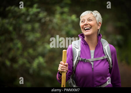 Porträt einer reifen Frau lachend vor Freude, als sie eine Wanderung im Wald genießt. Stockfoto