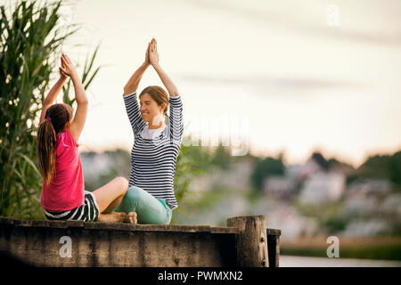 Mutter und Tochter Üben Yoga auf einem Pier. Stockfoto