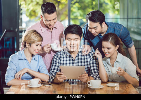 Lächelnd Freunde bei digital Tablet im Cafe suchen Stockfoto
