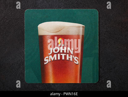 LONDON, Großbritannien - 22 August, 2018: John Smith's Papier Bier beermat Coaster auf schwarzem Hintergrund isoliert. Stockfoto