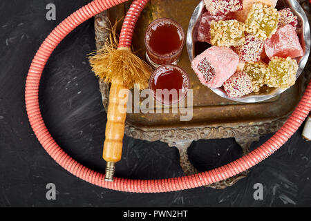 Satz von verschiedenen Turkish Delight in traditionellen silberne Schale auf Metall Fach in der Nähe von Shisha Schlauch schwarzen Hintergrund im Nahen und Mittleren Osten Dessert. Stockfoto