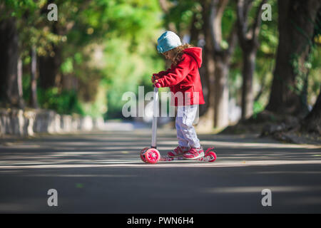 Das kleine Mädchen reitet der Roller in Park. Stockfoto