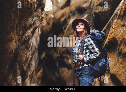 Reisen junge Frau mit braunen Hut, Plaid Shirt, Jeans und braune Stiefel mit Rucksack wandern im Canyon mit Moos auf Steinen nach dem Wandern, Konzept reisen Stockfoto