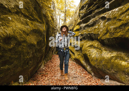 Reisen junge Frau mit braunen Hut, Plaid Shirt, Jeans und braune Stiefel mit Rucksack fertig zu nehmen Bild der wunderschönen Canyon mit Moos auf Steinen nach Wandern, Reisen Konzept Stockfoto