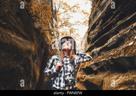 Reisen junge Frau mit braunen Hut, Plaid Shirt, Jeans und braune Stiefel mit Rucksack bis in die wunderschöne Schlucht mit Moos auf Steinen nach Wandern, Reisen Konzept Stockfoto