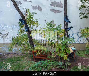 Berlin, Mitte. Bemalte Papier Vögel im Baum im Kinderspielplatz zwischen Gebäuden mit verwitterten alten Mauer Stockfoto