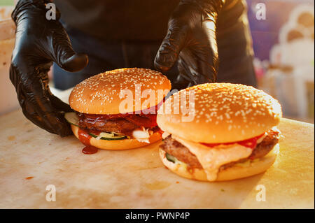 Zwei fertige Burger auf einem Holzbrett. Küche in der Straße geöffnet. Straße fast food Stockfoto