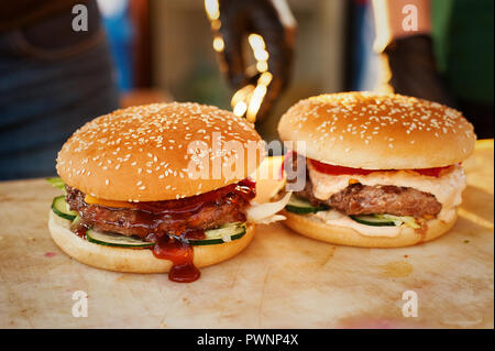 Zwei fertige Burger auf einem Holzbrett. Küche in der Straße geöffnet. Straße fast food Stockfoto