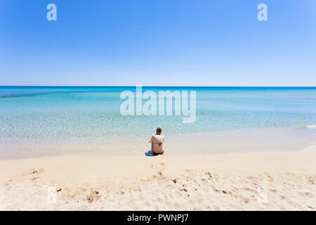 Lido Venere, Apulien, Italien - Eine junge Mutter sitzen am Strand mit Blick auf den Horizont Stockfoto