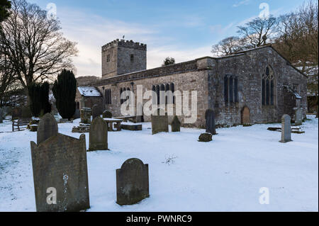 Schneereiche Winter Fassade von St. Michael und alle Engel Kirche mit Grabsteinen in verschneiten Kirchhof - Hubberholme, Yorkshire Dales, England, UK. Stockfoto