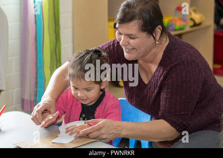 Alpine, Texas - Mari Rodriguez hilft Kindern mit einem Kunstprojekt in der zwei-jährigen Klassenzimmer an der Alpinen Community Center. Das Zentrum ist ein MISSI Stockfoto