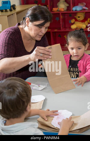 Alpine, Texas - Mari Rodriguez hilft Kindern mit einem Kunstprojekt in der zwei-jährigen Klassenzimmer an der Alpinen Community Center. Das Zentrum ist ein MISSI Stockfoto