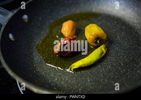 In der Pfanne, es gibt 4 verschiedene Peperoni und Öl, fertig gebraten werden. Stockfoto