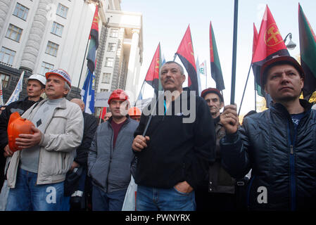 Bergleute halten Fahnen während eines Protestes, vor der Ukrainischen Ministerkabinett der Gebäude in Kiew. Berichten zufolge Tausende Menschen haben bei einem Protest von ukrainischen Trade Union Federation organisiert, fordert, steigende Löhne und Arbeitsbedingungen für Arbeitnehmer, der vom Staat finanziert. Demonstranten tragen Plakate lesen "Bildung ist die Zukunft der Ukraine", "Die nicht in der Schule arbeiten nicht in der Lage ist, uns zu "verstehen", der minimale Lohn ist Gefahr für Ihre Gesundheit", "Notwendigkeit eines Lehrers Gehalt geben, Ukrainische Gesetzgeber" und so weiter. Der Protest auf den Internationalen Tag für die Eradicat Stockfoto