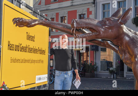 17 Oktober 2018, Brandenburg, Cottbus: Rainer Opolka, Künstler und Unternehmer, steht auf dem Altmarkt hinter einem bronze Wolf mit einem Hitlergruß. Mit einer Mahnwache auf der Cottbus Altmar mit einer Mahnwache auf dem Cottbuser Altmarkt der Bildhauer Opolka will gegen Hass und Gewalt zu demonstrieren. Am Mittwoch, den vier Bronze wolf Skulpturen und Informationstafeln errichtet wurden auf dem zentralen Platz im Zentrum der Stadt. Die Mahnwache in Cottbus gerichtet Opolka gegen was er als zunehmende Radikalisierung in der AfD. Die Partei ist unter Druck, weil die Bundesländer "Amt für den Schutz der Con Stockfoto