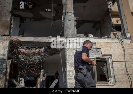 Beer Sheva, israelische Stadt Beer Sheva. 17 Okt, 2018. Ein israelischer Polizist untersucht ein Haus, das einen direkten Erfolg von einer Rakete angeblich durch militante Gruppen aus dem Gazastreifen abgefeuert litt, im Süden der Israelischen Stadt Beer Sheva, am Okt. 17, 2018. Israels militärische Sprecher sagte am Mittwoch, dass die Armee sieht die Zündung von zwei Raketen auf Israel früher am Morgen' einen schweren Vorfall." Credit: Jini/Xinhua/Alamy leben Nachrichten Stockfoto