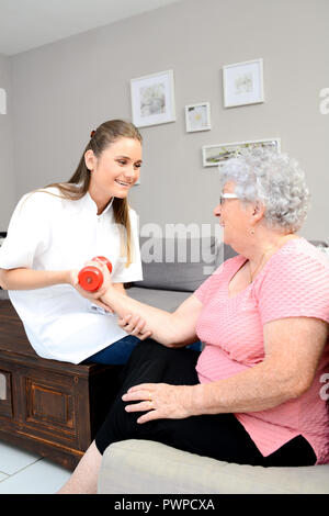 Junge Physiotherapeutin Krankenschwester ältere Frauen helfen, physische Rehabilitation zu Hause Stockfoto