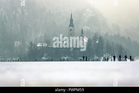 Gefrorenen See im Winter Bled. Menschen zu Fuß auf die Insel auf dickem Eis. Stockfoto