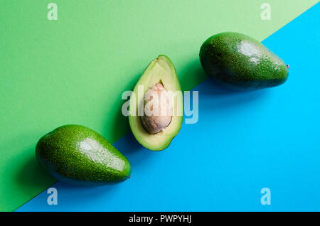 Organische Avocado mit Saatgut und ganze Früchte auf die Farbe blau und grün hinterlegt. Pop Art Design, kreative Sommer essen Konzept. Grüne Avocados Muster i Stockfoto