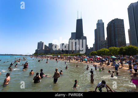 Menschen schwimmen im See Michigan am Oak Street Beach an einem Sommertag mit dem Chicago Skyline im Hintergrund - Chicago, IL Stockfoto