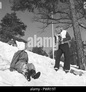 Winter in den 1940er Jahren. Eine junge Mutter ist Fotografieren ihre Tochter ein Wintertag. Die Kamera ist eine Rolleiflex. Schweden 1944. Foto Kristoffersson Ref F104-2 Stockfoto