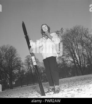 Winter in den 1940er Jahren. Eine junge Frau trägt die typischen 40er Jahre Wintersport Kleidung. In einem praktischen Wind Jacket, Ski Hosen und mit ein paar Ski und Stöcke gekleidet. Schweden 1948. Foto Kristoffersson ref Y10-4 Stockfoto