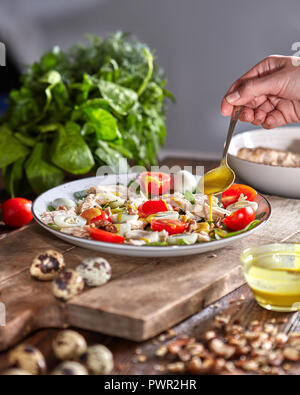 Frau gießen frisch zubereiteten Salat Sauce auf einem Holzbrett. Natürliche organische Diät essen. Stockfoto