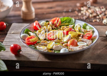 Frische hausgemachte Salate mit natürlichen Zutaten - organische sauber Gemüse, Hähnchen Fleisch und guail Eier, würzigen Senf in einer Platte auf einem Holzbrett. Stockfoto