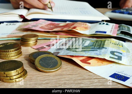 Euro-banknoten und -Münzen und Mann die finanziellen Berechnungen macht. Home Finanzen. Stockfoto