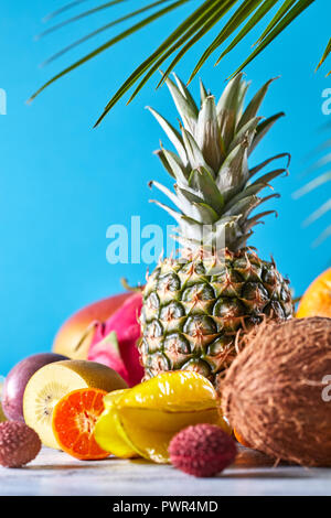 Gruppe von exotischen und tropischen Früchten. Mango, Drachenfrucht, Passionsfrucht, Kokosnuss, Ananas, Karambolen, kumquat auf blauem Hintergrund. Stockfoto
