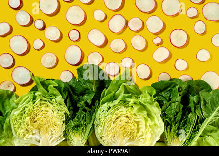 Kreative organische Muster von clices Radieschen und grünen Hälften verschiedener Arten von Salat - Romaine, Eisberg auf gelbem Hintergrund. Flach Stockfoto