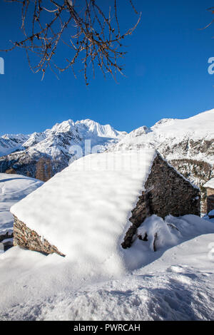 Hütte mit Schnee bedeckt mit Monte Disgrazia auf Hintergrund, Alpe dell'Oro, Valmalenco, Valtellina, Lombardei, Italien Stockfoto