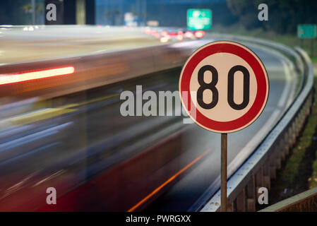 Lange Belichtung geschossen von Verkehrszeichen mit 80 km/h Höchstgeschwindigkeit auf der Autobahn voller Autos in motion blur während der Nacht Stockfoto