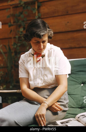 1950 s Bild der schönen Frau lesen Magazin auf einer Terrasse, CA, USA Stockfoto