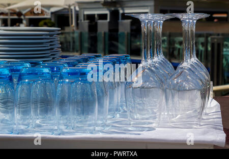 Blau getönte Gläser und Weingläser mit Platten in einem Restaurant am Yachthafen von Vilamoura Portugal gestapelt Stockfoto