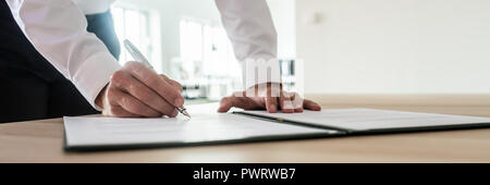 Panoramabild des Geschäftsmannes Unterzeichnung wichtiges Dokument oder Vertrag während an seinem Schreibtisch stehen. Stockfoto