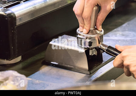 Nahaufnahme der männlichen Händen eines Barista stopfmaschine Kaffee in einem portafilter. Stockfoto