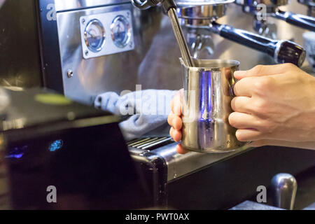 Nahaufnahme eines Barista männlichen Händen dampfende Milch auf eine Espressomaschine. Stockfoto