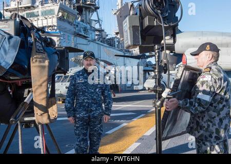 SYDNEY (1. Juli 2017) Kapitän Larry McCullen, kommandierender Offizier der Amphibisches Schiff, die USS BONHOMME RICHARD (LHD 6) spricht mit den Gastgebern 9 Nachrichten, eine australische Fernsehen morgen zeigen, aus dem Schiff Flight Deck während einer Live-Übertragung. Bonhomme Richard machte einen Port zu Sydney als Teil der Talisman SABRE 2017, der eine zweijährige USA - Australien bilaterale militärische Übung, verbindet ein Feld Training und Kommandostellenübung Interoperabilität und zur Stärkung der Grundsätze der amerikanisch-australische Bündnis zu wahren. Stockfoto